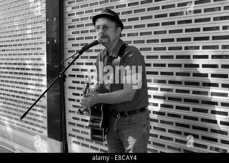 Mâle mature musicien ambulant avec guitare chanter dans un centre-ville angleterre uk Banque D'Images