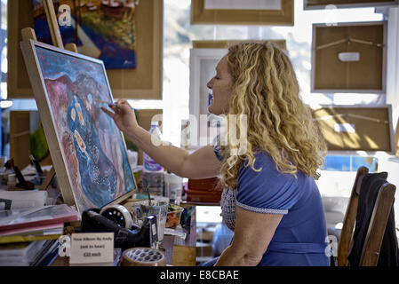 Femme artiste peinture. Gina Farrell au travail dans son studio. Polperro Cornwall Angleterre Royaume-Uni Banque D'Images