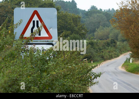 Route Narrows Road sign avec les mots la circulation venant en sens inverse au milieu d'un sous-bois en bordure de la route cachée par Banque D'Images