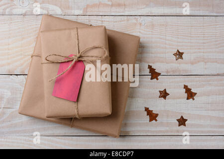 Un high angle view of plain brown paper wrapped presents avec red tags sur une table rustique blanc. Les petits ornements de métal rouillé à st Banque D'Images