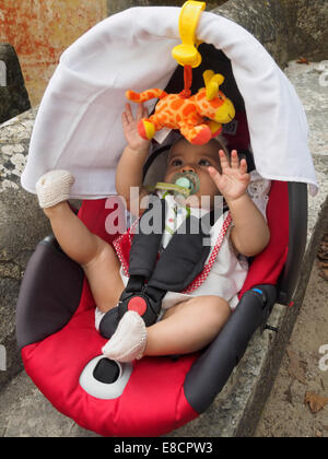 Baby Playing with toy girafe tout en attaché sur un siège de voiture Banque D'Images
