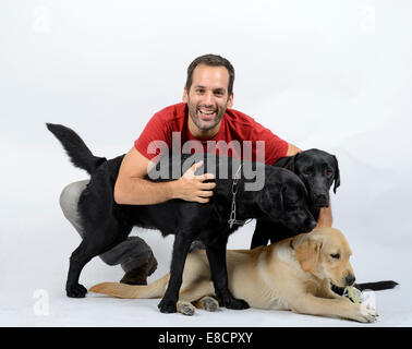 Heureux jeune homme avec trois chiens labrador retriever Banque D'Images