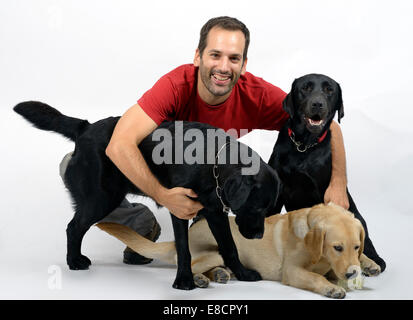 Heureux jeune homme avec trois chiens labrador retriever Banque D'Images