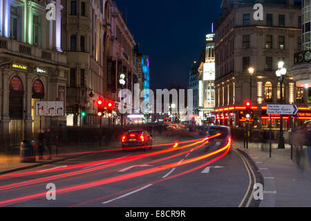 Une voiture et taxi noir s'arrêter à un feu rouge dans le centre de Londres pour faire light trails Banque D'Images