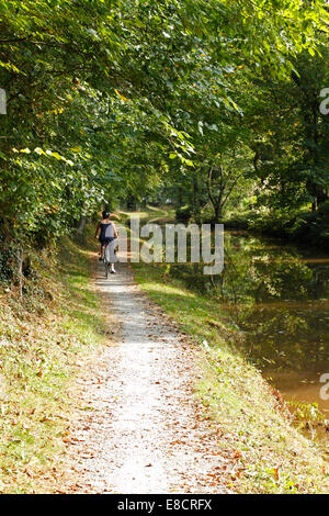 Jeune femme à vélo sur un chemin de halage du canal Banque D'Images
