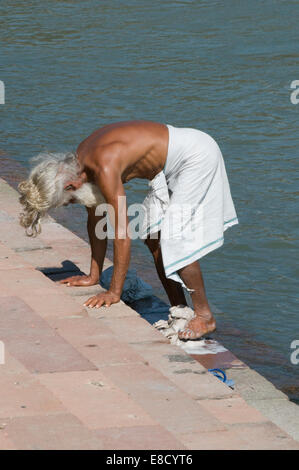 Sadhu barbu aux cheveux blancs et à laver les vêtements dans le Gange Rishikesh au nord de l'Inde Uttarakanth Banque D'Images