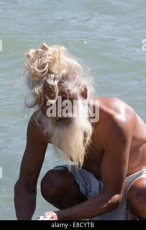 Sadhu barbu aux cheveux blancs et à laver les vêtements dans le Gange Rishikesh au nord de l'Inde Uttarakanth Banque D'Images