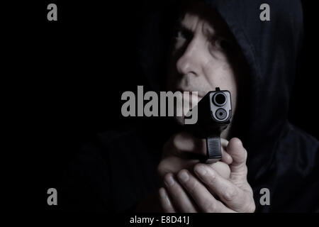 Libre vue avant du pistolet en face de l'homme désespéré en fond sombre Banque D'Images