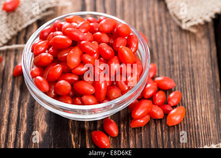 Quelques baies de Goji frais (également connu sous le nom de Wolfberry) vintage sur fond de bois Banque D'Images