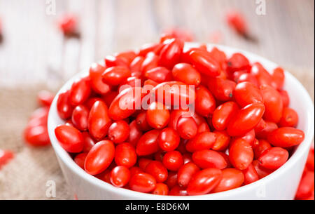 Quelques baies de Goji frais (également connu sous le nom de Wolfberry) vintage sur fond de bois Banque D'Images