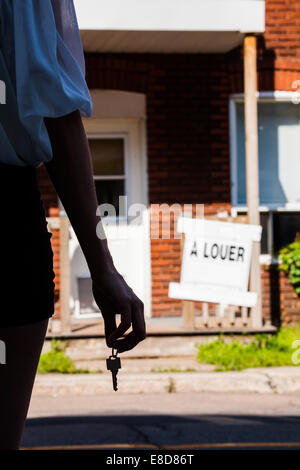 Jeune femme debout avec touches en face de son nouvel appartement Banque D'Images