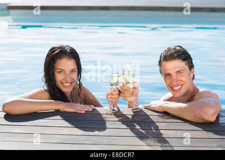 Couple toasting with champagne in swimming pool Banque D'Images