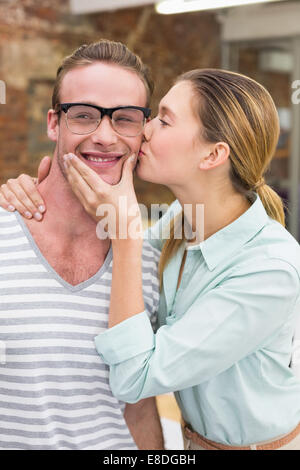 Woman kissing happy man in office Banque D'Images