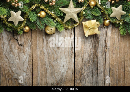 Branches de sapin avec boîte cadeau d'or, boules et étoiles sur fond de bois Banque D'Images