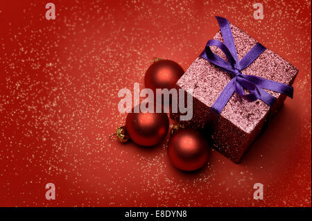 Boîte cadeau coloré de rouge, des boules de Noël sur fond rouge Banque D'Images