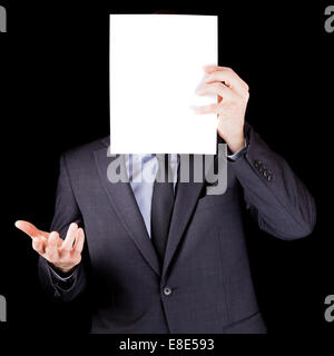 Businessman holding an empty feuille de papier en face de son visage isolé sur fond noir Banque D'Images