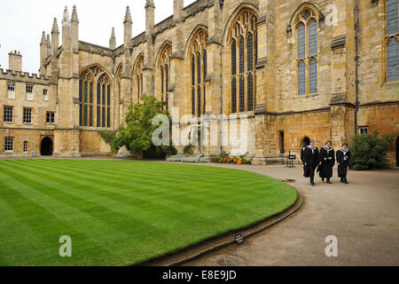 3 diplômés portant des robes sub fusc marchant dans le quad à l'intérieur du New College Oxford, qui fait partie de l'Université d'Oxford, Royaume-Uni Banque D'Images