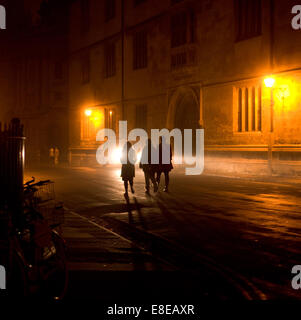 Scène de nuit dans la ville historique d'Oxford. 3 étudiants marcher, Old Bodleian Library, Radcliffe Camera .prêt de vélos en premier plan silhouettes Banque D'Images