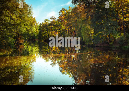 Journée ensoleillée en extérieur parc avec lac et arbres aux couleurs automnales sous réflexion ciel bleu. Incroyable de couleurs automne nature Banque D'Images