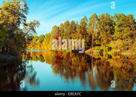 Journée ensoleillée en extérieur parc avec lac et arbres aux couleurs automnales sous réflexion ciel bleu. Incroyable de couleurs automne nature Banque D'Images