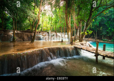 Jangle paysage de forêt tropicale humide paysage avec pont de bois et de l'eau turquoise magnifique cascade de Kuang Si waterfall. Banque D'Images