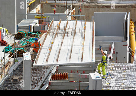 L'abaissement de la grue les planchers en béton grand panneau en position pendant la construction de nouvelles maisons dans les immeubles à appartements Banque D'Images