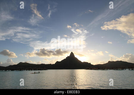 Outrigger au coucher du soleil à Bora Bora, Polynésie Française avec silhouette de montagne derrière Banque D'Images