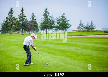 Golfeur mature sur un parcours de Golf de frapper une balle (moment de l'impact) Banque D'Images