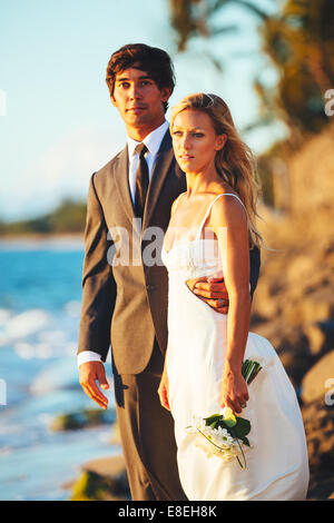 Beau couple de mariés sur la plage au coucher du soleil Banque D'Images