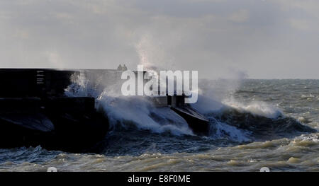 Brighton, Sussex, UK. 7 octobre, 2014. Météo britannique. Deux personnes peuvent être vus marcher dangereusement près de vagues se brisant sur le port de plaisance de Brighton ce matin d'automne comme ensembles météo dans l'ensemble de la Grande-Bretagne . Crédit : Simon Dack/Alamy Live News Banque D'Images