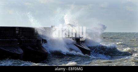 Brighton, Sussex, UK. 7 octobre, 2014. Météo britannique. Deux personnes peuvent être vus marcher dangereusement près de vagues se brisant sur le port de plaisance de Brighton ce matin d'automne comme ensembles météo dans l'ensemble de la Grande-Bretagne . Crédit : Simon Dack/Alamy Live News Banque D'Images