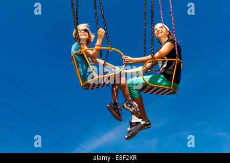 Adolescents deux filles sur le carrousel d'oscillation de chaîne Banque D'Images