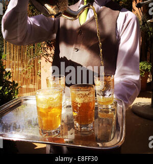 Le Maroc, Marrakech, Waiter pouring tea au cours de cérémonie du thé Banque D'Images