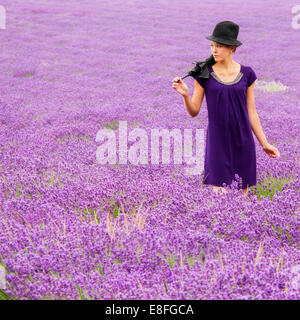 Femme avec chapeau et parapluie debout dans champ de lavande Banque D'Images