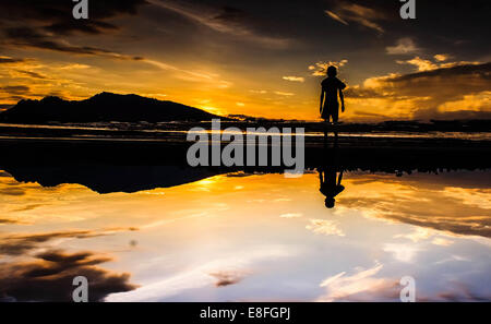 Silhouette of man standing on beach at sunset Banque D'Images