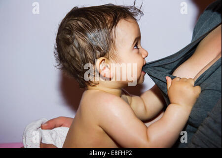 Baby Girl biting et tirant la mère t-shirt Banque D'Images
