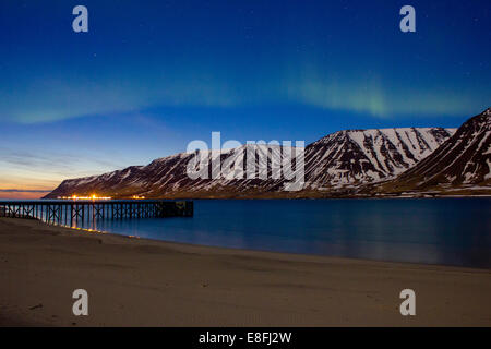 Lumières du nord sur Westfjords avec la ville de Flateyri au loin, l'Islande