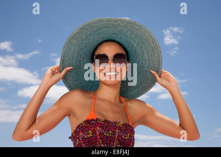 Portrait d'une femme souriante tenant son chapeau de paille sur la plage, le Cap, le Cap occidental, Afrique du Sud Banque D'Images