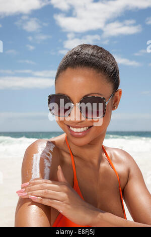 Portrait de femme souriante appliquant de la crème solaire, Cape Town, Western Cape, Afrique du Sud Banque D'Images