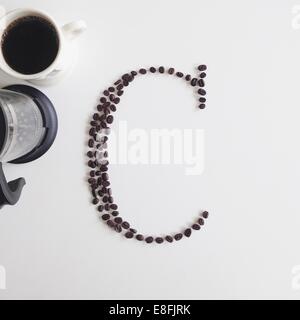 Lettre C faite de grains de café à côté d'une tasse de café et d'une cafetière Banque D'Images