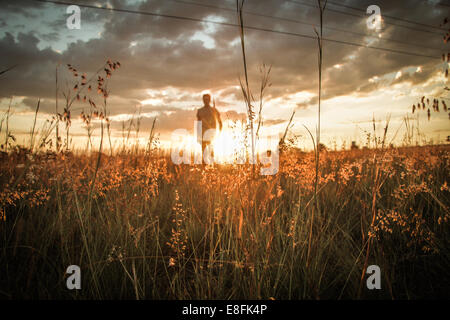 Homme de terrain comme le coucher du soleil Banque D'Images