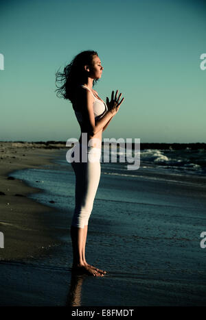 Vue latérale du woman standing on beach faisant du yoga avec les mains en position de prière Banque D'Images