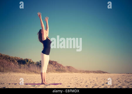 Woman practicing yoga on beach Banque D'Images