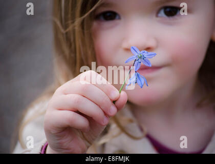 Portrait rapproché d'une fille tenant une fleur violette, Angleterre, Royaume-Uni Banque D'Images