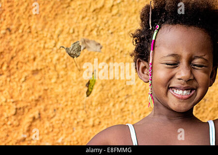 Portrait of a smiling girl contre mur jaune Banque D'Images