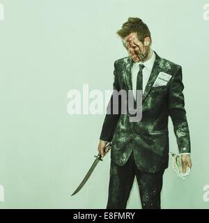 Homme sanglant dans un costume sale tenant une épée et une poignée d'argent Banque D'Images