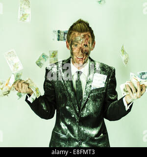 Homme sanglant dans un costume sale jetant de l'argent dans l'air Banque D'Images