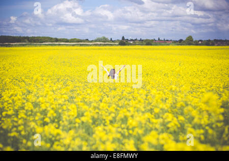 Girl standing in rapeseed field Banque D'Images