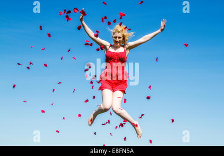 Portrait de femme sautant en l'air avec des pétales de rose Banque D'Images