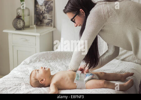 Femme de changer la couche de son fils Banque D'Images